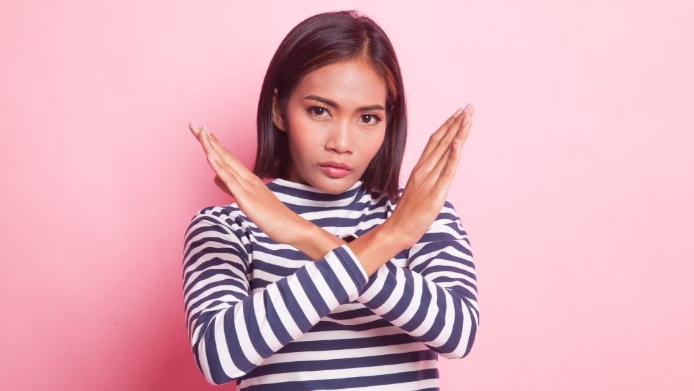 腕で大きなバッテンを作ってNGサインを出している女性