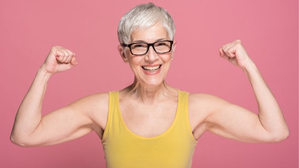 笑顔で筋肉を見せるお年寄りの女性